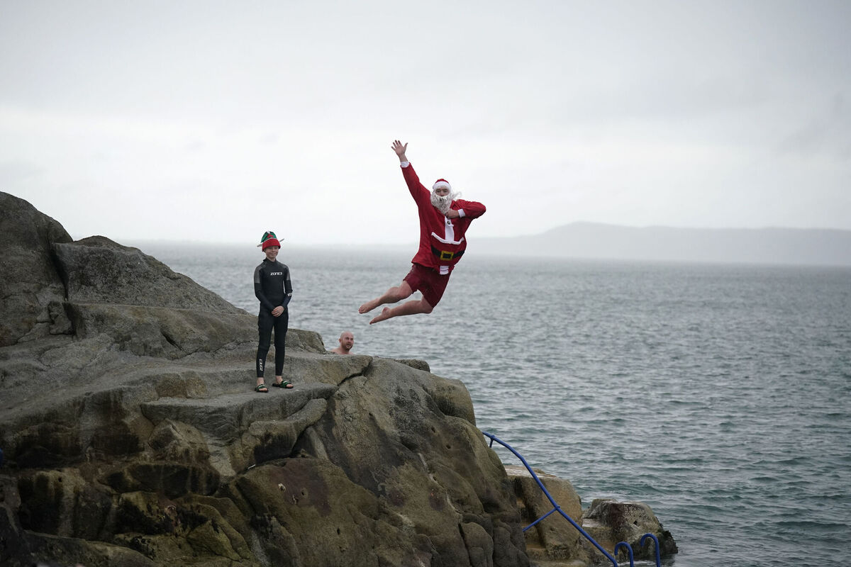 Patrick Corkery dressed as Santa and his son Matthew, 12, dressed as an elf, taking part in the annual Christmas Day swim at the Forty Foot. Picture: Niall Carson/PA Wire