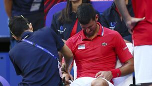 <p>A trainer massages the right arm of Novak Djokovic.</p>