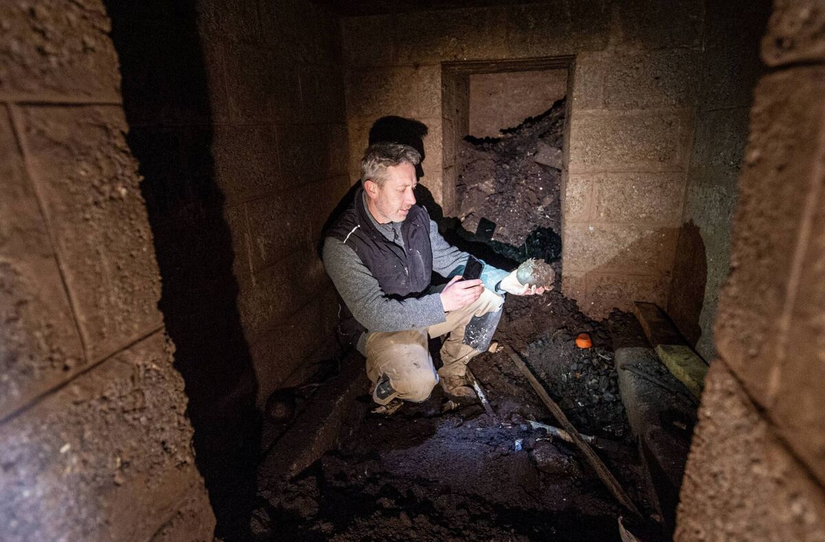 Landscaper Aidan Carroll looking at items that have been left in the main room of the shelter. The room behind was probably a store. 