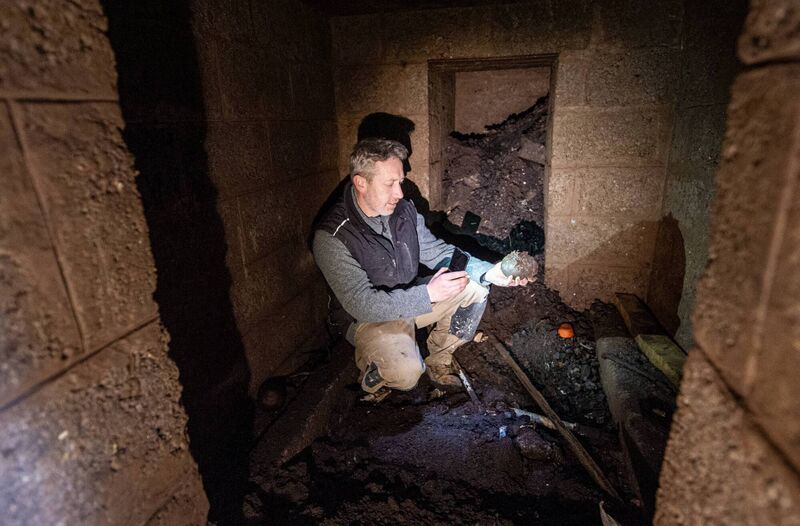 Landscaper Aidan Carroll looking at items that have been left in the main room of the shelter. The room behind was probably a store. Landscaper Aidan Carroll looking at items that have been left in the main room of the shelter. The room behind was probably a store.