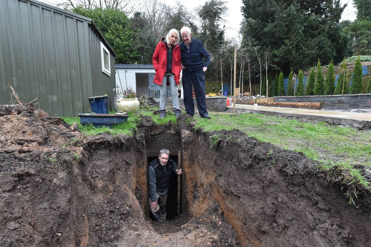 Jean Walsh and her neighbour Jerry Coughlan standing in the garden above the shelter with landscaper Aidan Carroll emerging from the shelter. 