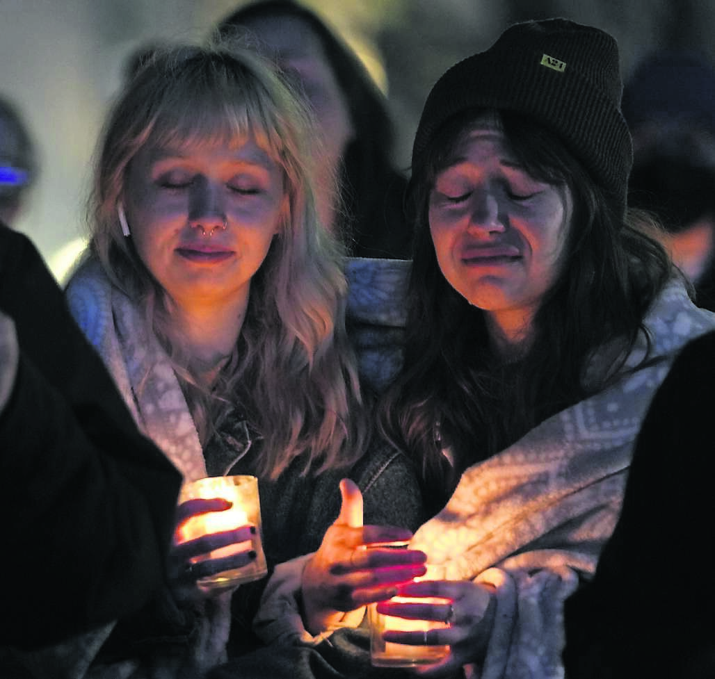 GRIM REALITY: Abbie Lewis, left, and Jackie Batista-Martinez attend a candlelight vigil for the victims of a shooting at a Kansas City Chiefs Super Bowl victory rally last week. More than 20 people were injured and one woman was killed in the shooting near Union Station. Pic: Charlie Riedel, AP
            