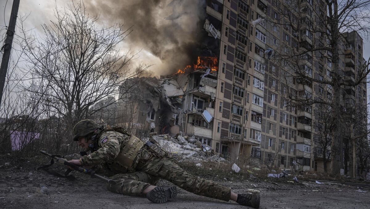 A Ukrainian police officer takes cover in front of a burning building that was hit in a Russian airstrike in Avdiivka, Ukraine. Picture: AP Photo/Evgeniy Maloletka