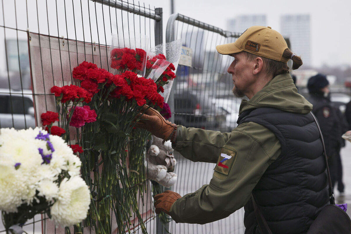 A man places flowers on the fence near the Crocus City Hall on the western edge of Moscow, Russia, Saturday, March 23, 2024. (AP Photo/Vitaly Smolnikov)