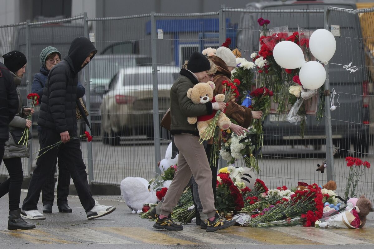 People place flowers and toys at the fence next to the Crocus City Hall, on the western edge of Moscow, Russia, Saturday, March 23, 2024, following an attack Friday, for which the Islamic State group claimed responsibility. (AP Photo/Vitaly Smolnikov)