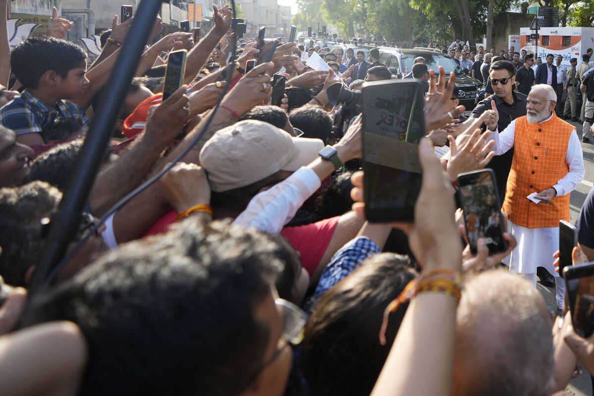 Indian Prime Minister Narendra Modi, right, talks with people as he arrives to cast his vote during the third phase of general elections, in Ahmedabad, India.