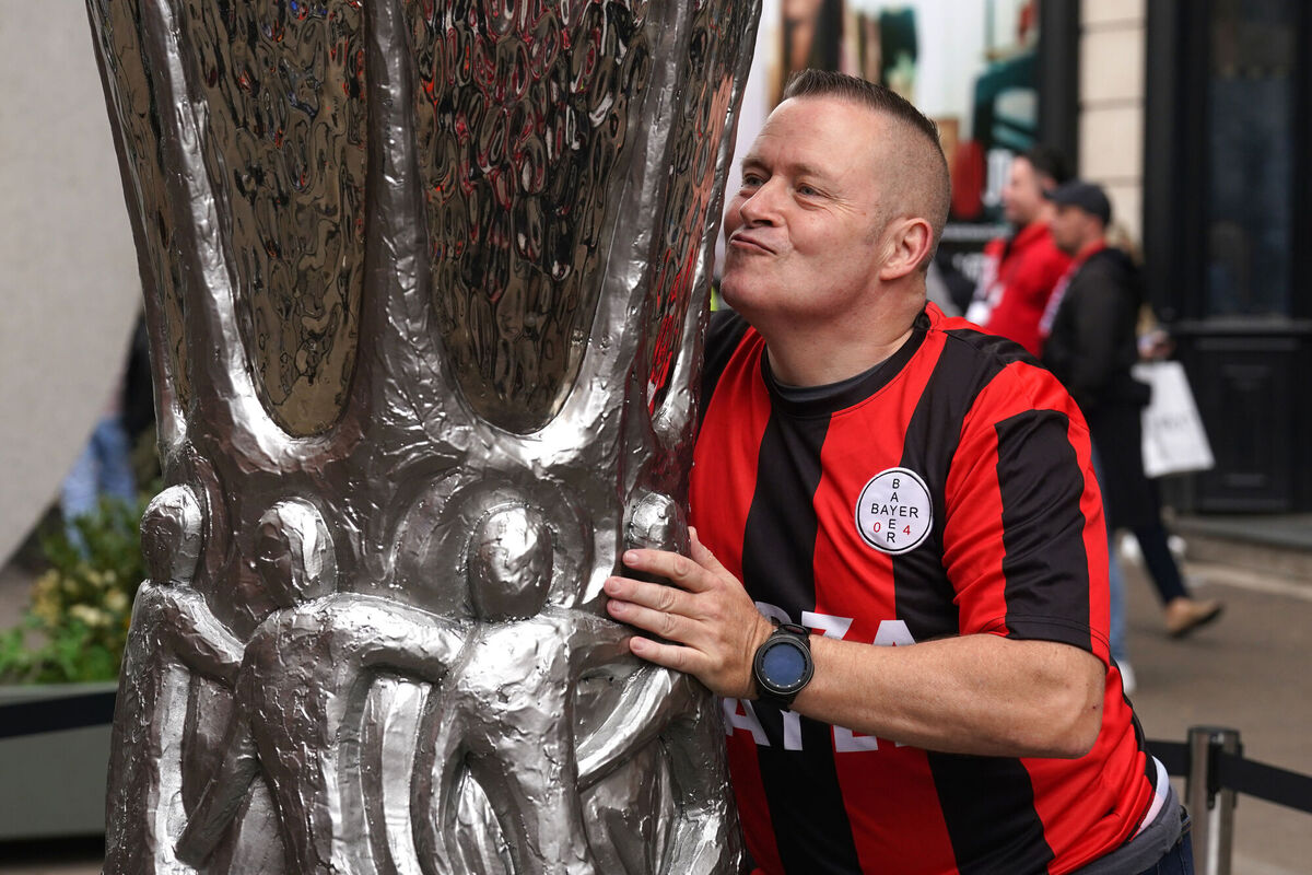 A Bayer Leverkusen fan kisses a replica of the Europa League trophy.