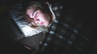 Depressed teenager on his phone in the dark.