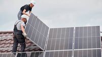 Man worker mounting solar panels on roof of house.