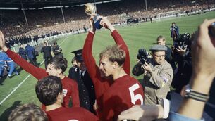 <p>Martin Peters and Jack Charlton celebrate on the pitch after England's victory in the 1966 World Cup final at Wembley, 30th July 1966. Captain Bobby Moore, obscured by Jack Charlton, holds the Jules Rimet trophy aloft. (Photo by Central Press/Hulton Archive/Getty Images)</p>
