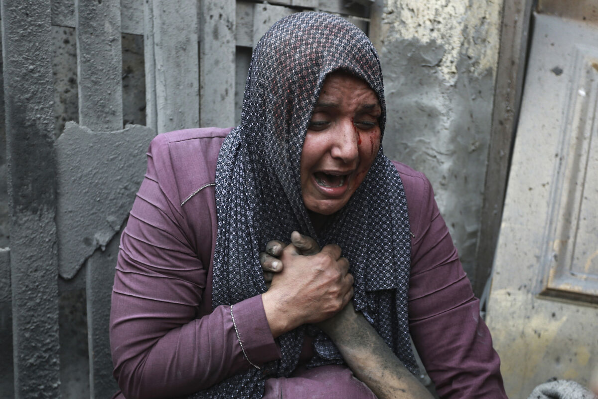 A wounded woman weeps as she holds the hand of her dead relative outside her home following the same series of Israeli airstrikes that killed the Khudair family in Gaza in October, 2023. Picture: Abed Khaled/AP