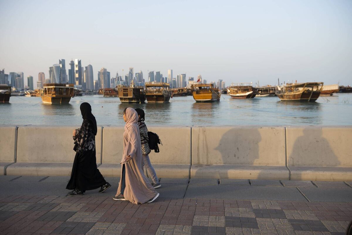 Three Arab women walk at sunset along the corniche in Doha, Qatar.