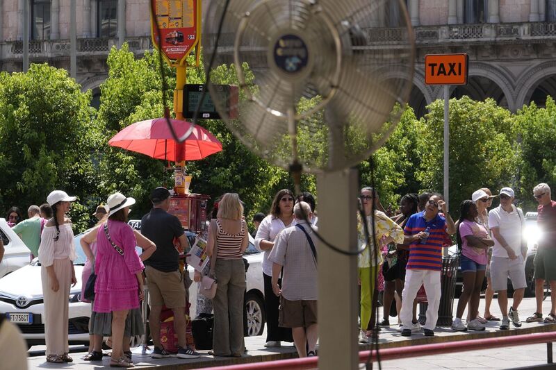 Tourists wait for a bus under the sun in Milan, Italy. Picture: AP Photo/Luca Bruno Tourists wait for a bus under the sun in Milan, Italy. Picture: AP Photo/Luca Bruno