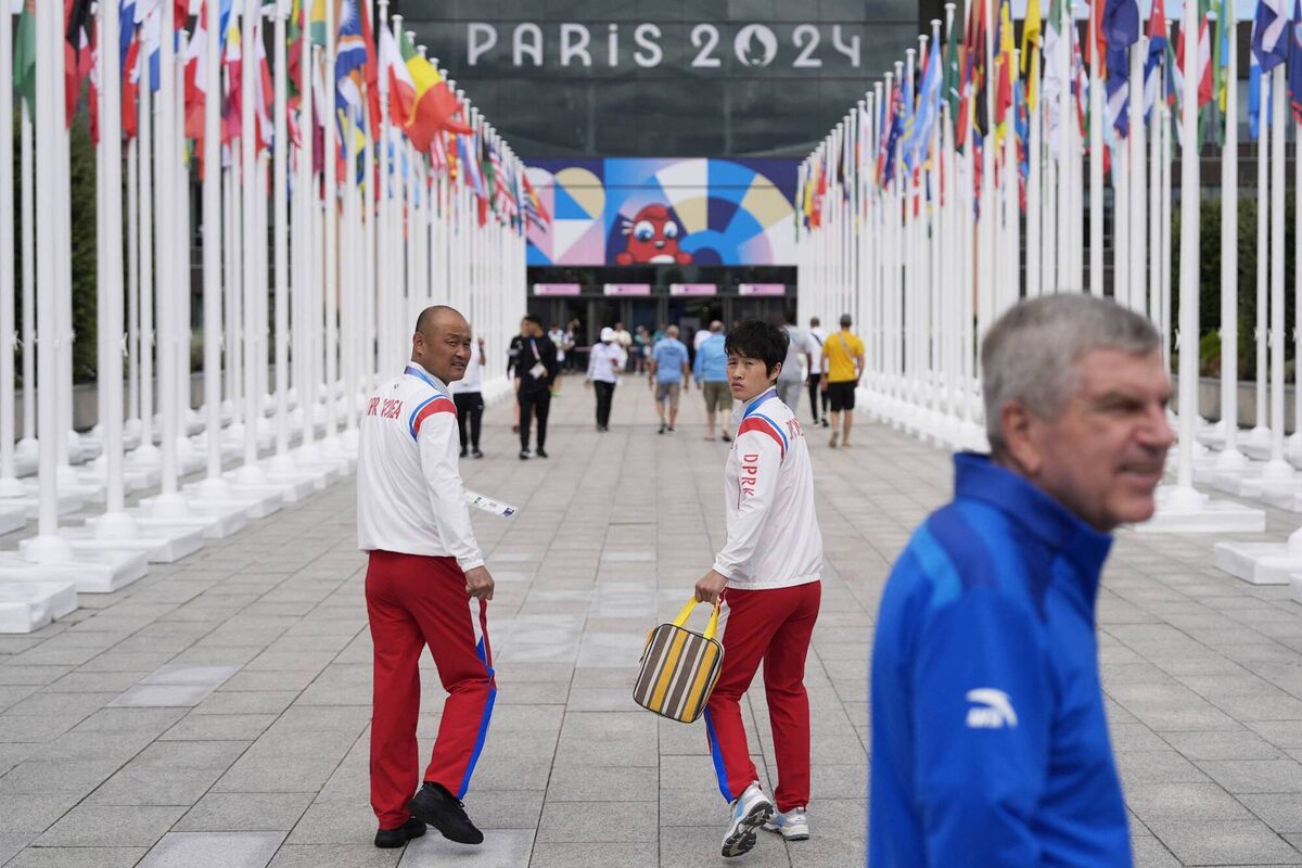 Members of the North Korean Olympic team look back as IOC President Thomas Bach (R) tours the Olympic Village ahead of the Paris 2024 Olympic Games, in Saint-Denis, near Paris on July 22, 2024. (Photo by David Goldman / POOL / AFP) (Photo by DAVID GOLDMAN/POOL/AFP via Getty Images)