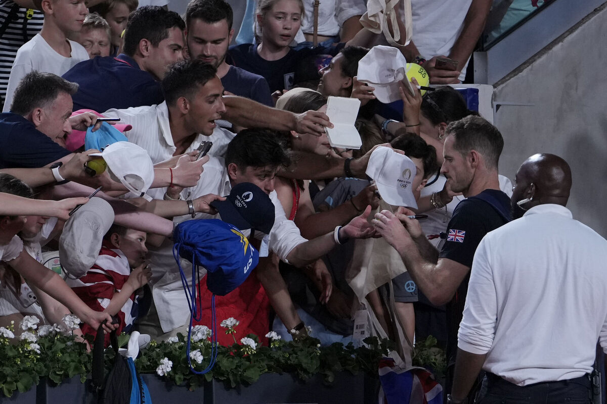 Andy Murray of Britain signs autographs after he and his partner Daniel Evans defeated by Taylor Fritz and Tommy Paul of the United States in the men's doubles quarterfinals tennis match, at the 2024 Summer Olympics, Thursday, Aug.1, 2024, at the Roland Garros stadium in Paris, France. (AP Photo/Andy Wong)