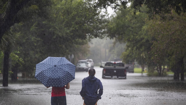 People wade into the flood waters from Tropical Storm Debby (Henry Taylor/The Post And Courier via AP)