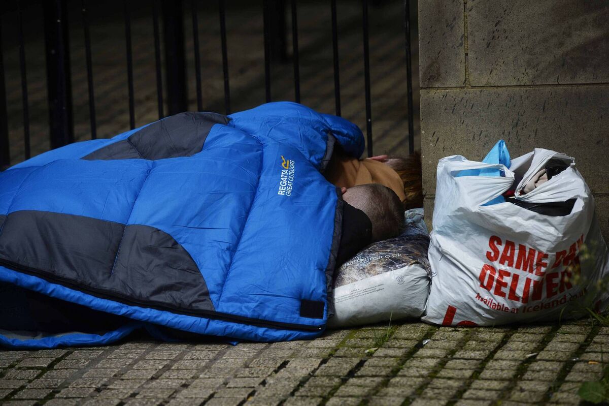 A homeless couple sleep on a corner as PSNI officers line the streets as two protests are scheduled to take place in Belfast city centre.