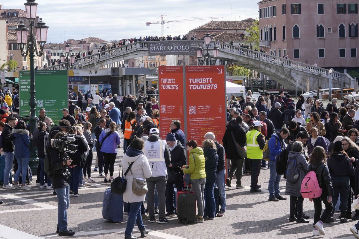 Stewards check tourists' QR code access outside the main train station in Venice. The €5 entry fee, which was introduced as a pilot program between April and mid-July, is expected to be re-introduced in 2025 on a permanent basis and possibly doubled. Photo: AP/Luca Bruno