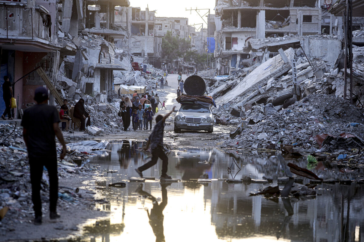 Displaced Palestinians walk past sewage flowing in the streets of Khan Younis. File picture: AP