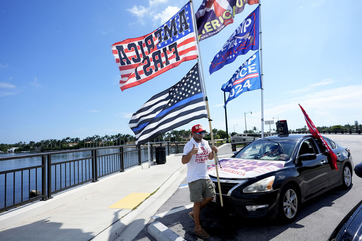 Justin Navarez, of Lake Worth, Fla. puts up flags on his vehicle outside of the Mar-a-Lago estate after the apparent assassination attempt of Republican presidential nominee and former President Donald Trump Monday, Sept. 16, 2024, in Palm Beach, Fla. (AP Photo/Lynne Sladky)