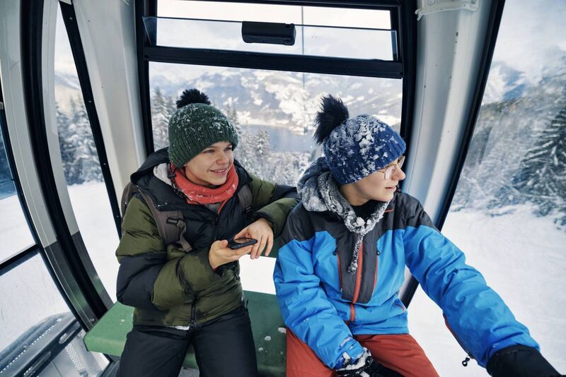 Teenagers in a gondola lift over a resort in les Trois Vallées