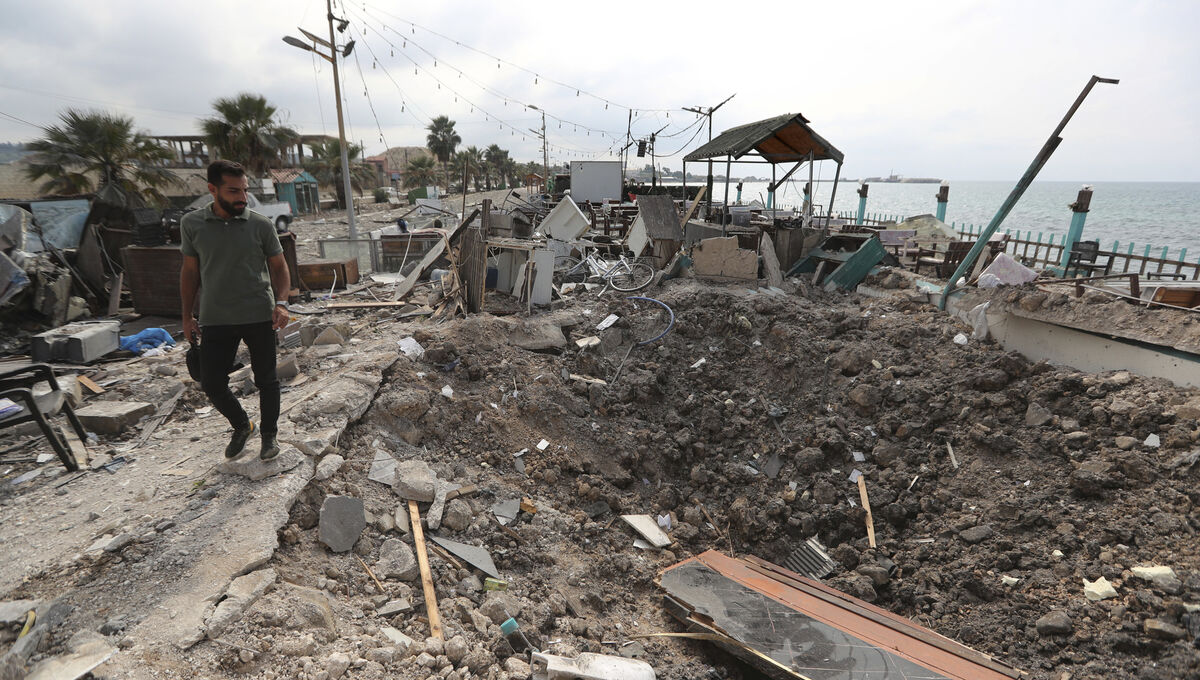 A man walks past a crater caused by an Israeli airstrike that hit a seaside coffee shop in Ghaziyeh town, Lebanon, on Sunday. Picture: Mohammed Zaatari/AP