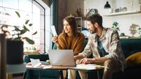 Doing Accounting at Home: Happy Couple Using Laptop Computer, Sitting on Sofa in Apartment. Young Family Filling Tax Forms, Mort