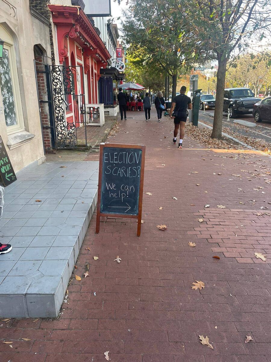 On Pennsylvania Avenue, a ‘Make America Great Again’ hat-wearing outlier attracts all kinds of rubbernecking and curious stares. The adjacent marijuana shop bears a poster offering help to the ‘election scaries.’ 