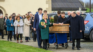 <p>Jon Kenny's coffin is escorted to the adjoining cemetery by his wife Margy and son Aran along with other family members after the funeral mass today. Picture: Dan Linehan</p>