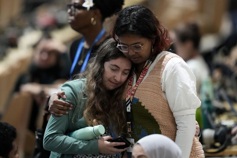 Attendees embrace while attending a closing plenary session at the COP29 U.N. Climate Summit, Sunday, Nov. 24, 2024, in Baku, Azerbaijan. (AP Photo/Rafiq Maqbool)