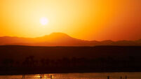 People walking on beach during sunset over Marsa Alam in Egypt with lapping waves over the reef in the foreground