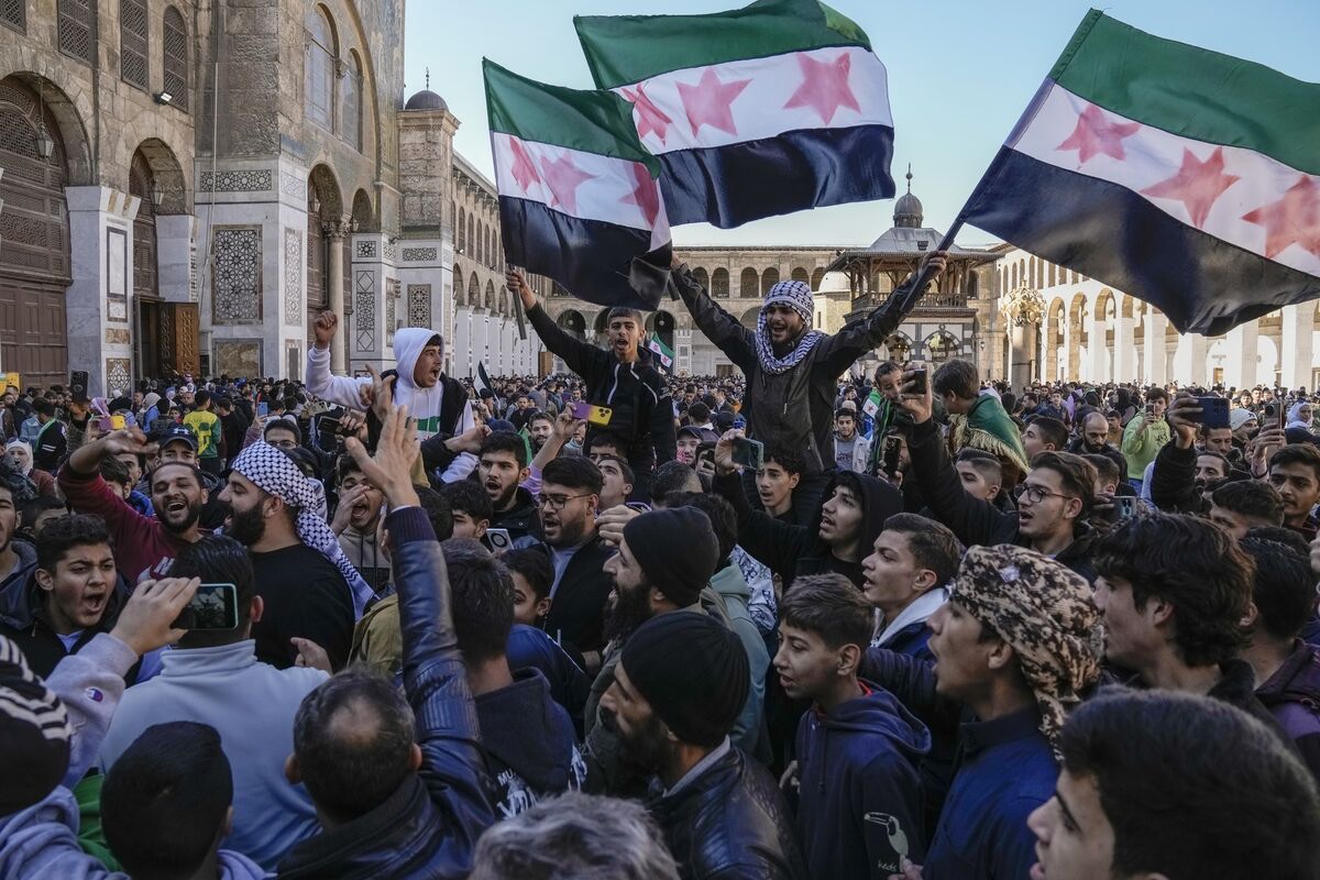 Syrians wave the new Syrian flag as they gather for Friday prayers at the Umayyad mosque in Damascus last Friday. Picture: AP/Leo Correa