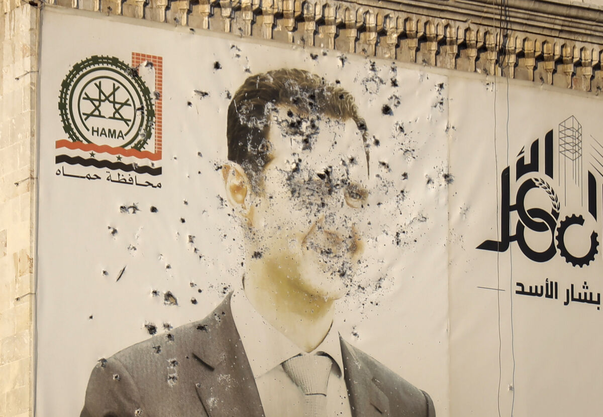 An image of Syrian president Bashar Assad, riddled with bullets, on the facade of the provincial government office in the aftermath of the opposition's takeover of Hama. Picture: AP/Omar Albam