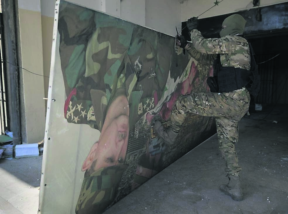 A Syrian rebel fighter removes a poster of ousted Syrian President Bashar Assad at the entrance to the notorious security detention centre called Palestine Branch in Damascus in December. Photo: AP/Hussein Malla