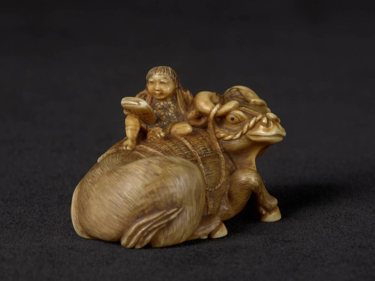 An ivory c1880 netsuke in the shape of an ox and a herd boy reading signed by Gyokkosai at Chester Beatty.