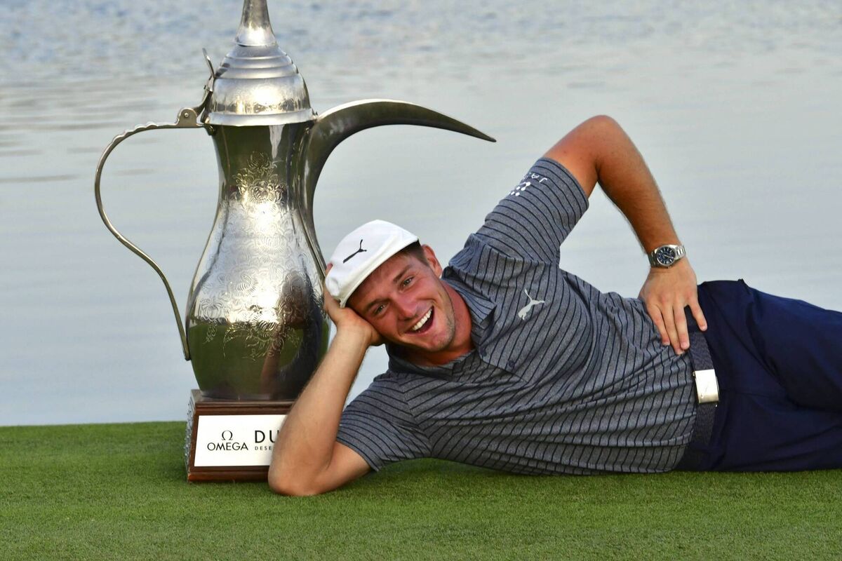 Bryson Dechambeau poses with the winner's trophy while celebrating his victory in the the Dubai Desert Classic.