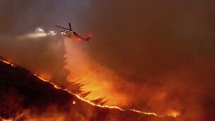 <p>Water is dropped by helicopter on the Kenneth Fire in the West Hills section of Los Angeles. Picture: AP Photo/Ethan Swope</p>