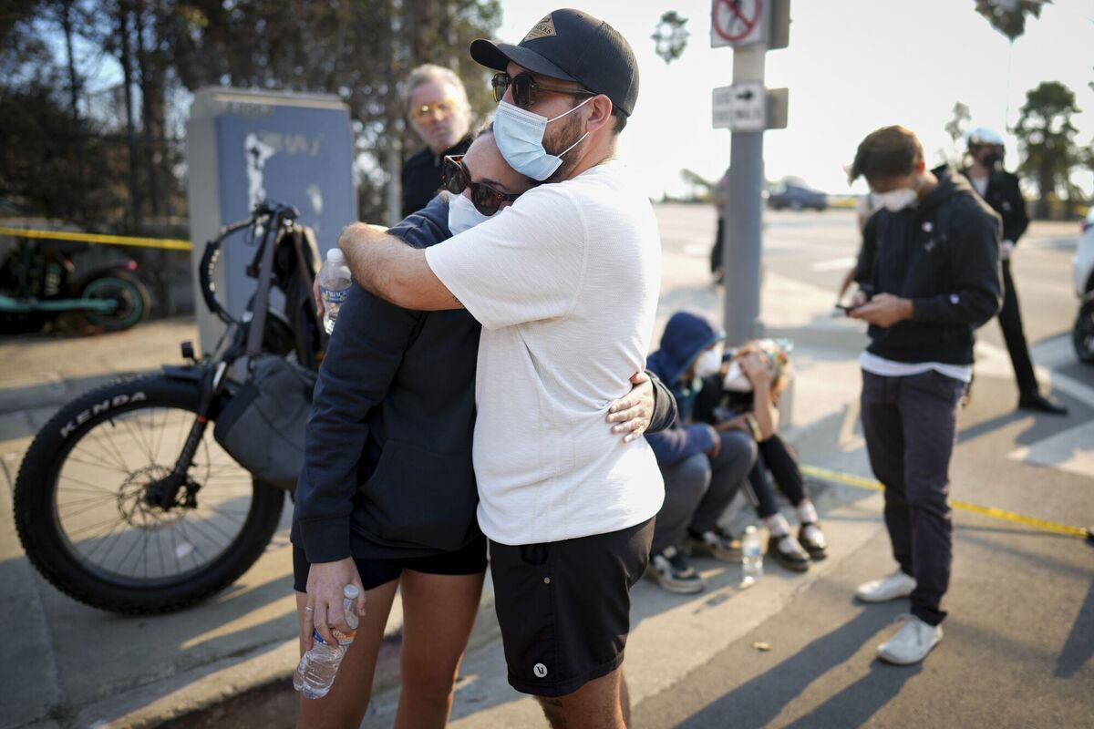 Ethan Sarani, and his fiancée Hannah Simon hug as they wait for access to their community in the aftermath of the Palisades Fire in the Pacific Palisades neighborhood of Los Angeles, Friday, Jan. 10, 2025. (AP Photo/Eric Thayer)