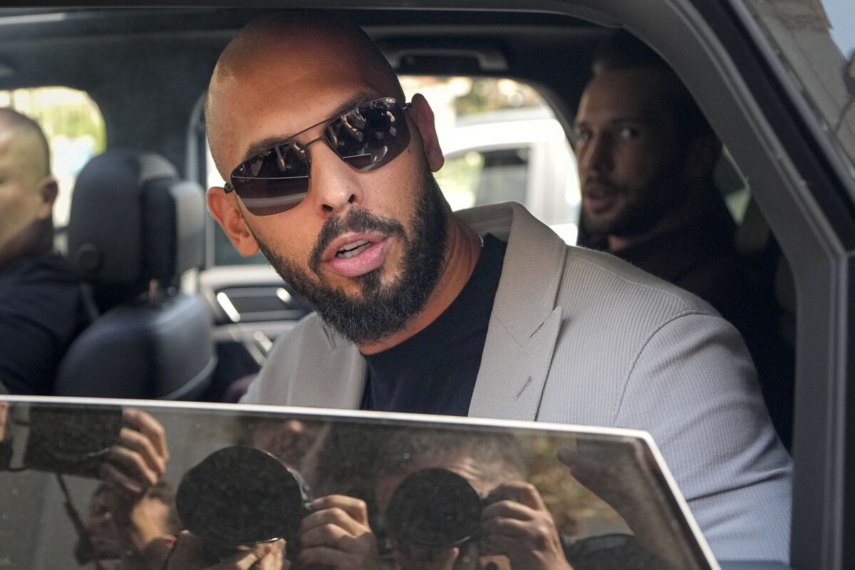 Andrew Tate sits in a car and talks to reporters surrounding his car after exiting the Court of Appeals building, after a hearing, in Bucharest, Romania, Wednesday, Sept. 4, 2024. (AP Photo/Vadim Ghirda)