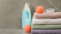 iStock-1446225239.jpg Dryer balls, detergents and stacked clean towels on grey marble table. Space for text