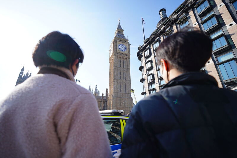 People watch a man with a Palestine flag after he climbed up Elizabeth Tower, which houses Big Ben at the Palace of Westminster in London. Picture: James Manning/PA Wire