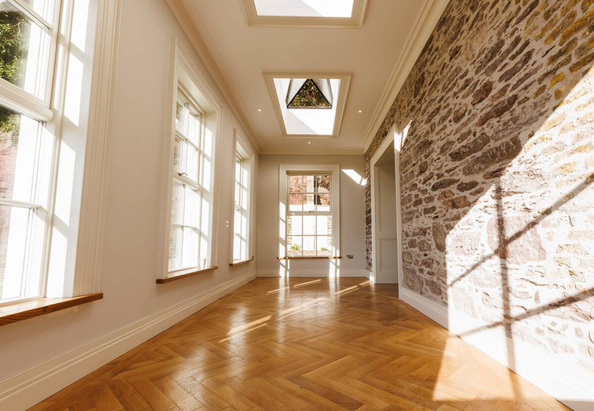 The hallway/entry with herringbone floor and old sandstone wall and overhead roof light.