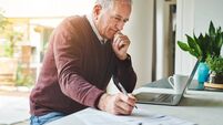 Shot of a senior man sitting alone and using his laptop to calculate his finances at home