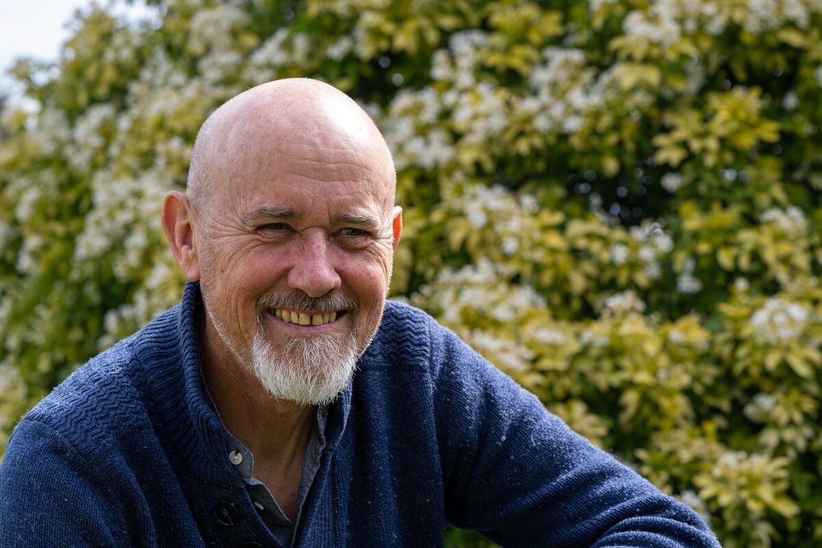 A smiling Jim Wilson at his garden in Blathan, Cobh, framed by a flowering bush as spring reaches its peak. Jim is best known for his work as a wildlife educator, author and advocate for Irish biodiversity. Picture: Chani Anderson A smiling Jim Wilson at his garden in Blathan, Cobh, framed by a flowering bush as spring reaches its peak. Jim is best known for his work as a wildlife educator, author and advocate for Irish biodiversity. Picture: Chani Anderson