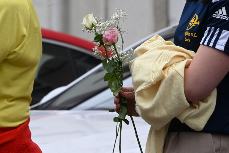 A mourner holding flowers in the guard of honour for Ellen Cassidy by local running and swimming clubs. Picture: Larry Cummins A mourner holding flowers in the guard of honour for Ellen Cassidy by local running and swimming clubs. Picture: Larry Cummins
