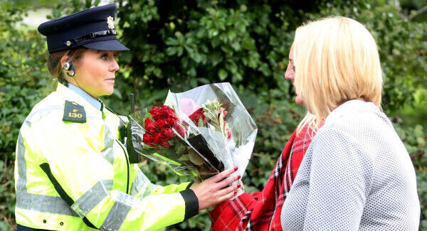 A woman leaves flowers with gardaí to place at the scene of the fire on Glenamuck road. Picture: Sam Boal/Rollingnews.ie