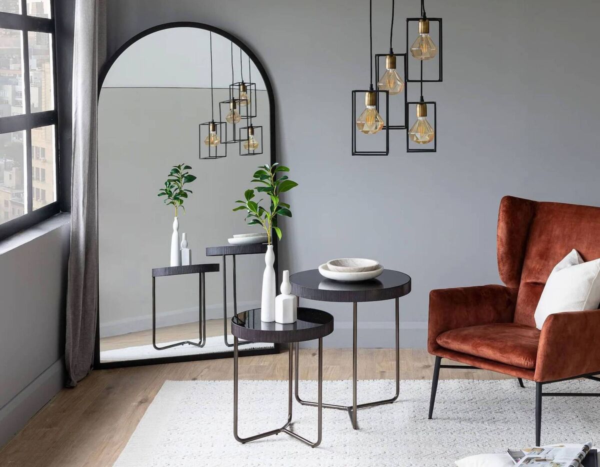 A massive mirror magnifies natural light in this cool pale grey colour scheme, opening up an otherwise blank corner; Chrisley Arch Mirror, €239.40, Ezlivingfurniture.ie.