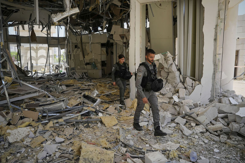 Israeli border police officers walk at the entrance of a residential building hit by a missile launched from Iran, in Petah Tikva, Israel, Monday, June 16, 2025. (AP Photo/Baz Ratner)