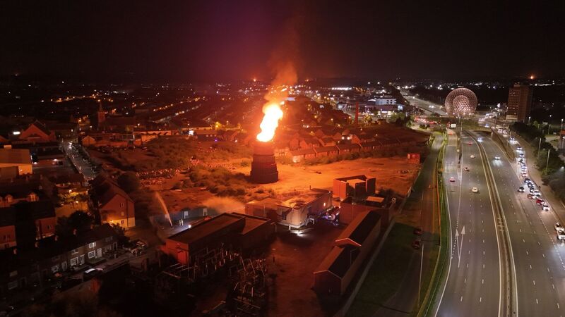 Firefighters work to protect an electricity sub station as a Controversial bonfire at Meridi Street, off the Donegall Road in Belfast is lit. Picture: Niall Carson/PA Wire