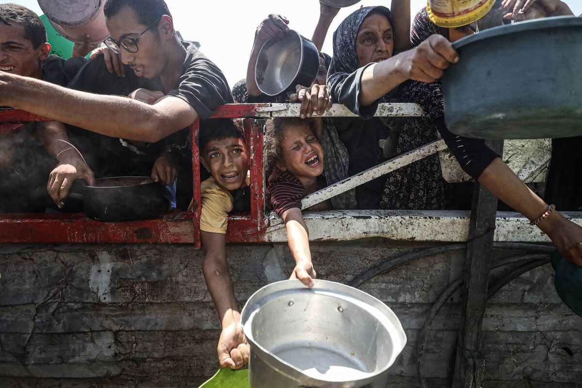 Palestinians carrying pans gather to receive hot meals, distributed by a charity organisation in Gaza City. Picture: Khames Alrefi/Anadolu via Getty Images